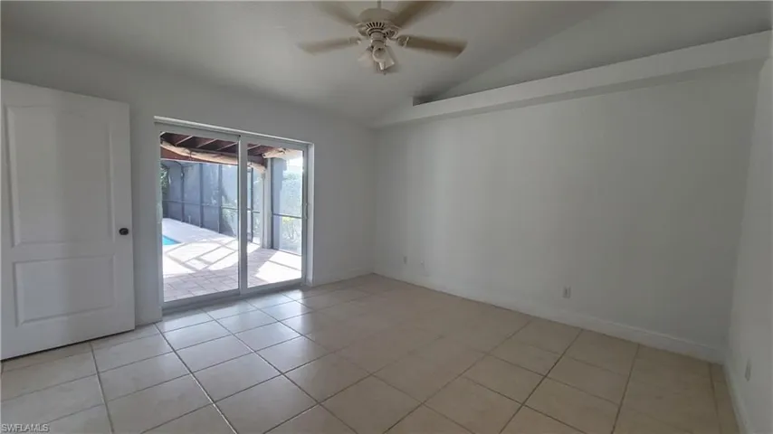 Spare room featuring ceiling fan, light tile patterned floors, and vaulted ceiling