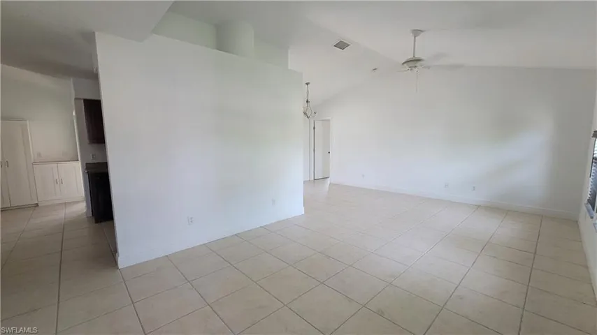 Empty room featuring ceiling fan, light tile patterned floors, and vaulted ceiling