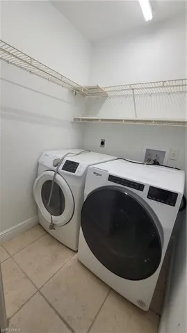 Laundry area with separate washer and dryer and light tile patterned flooring