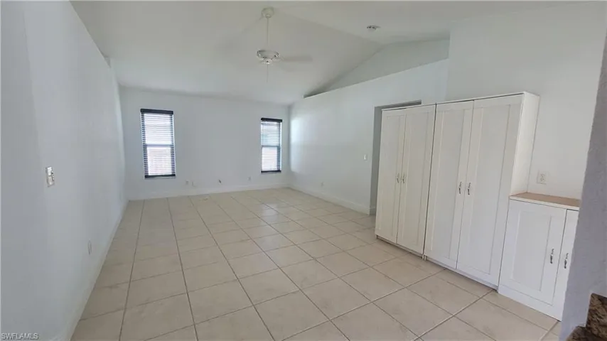 Unfurnished bedroom with lofted ceiling and light tile patterned flooring