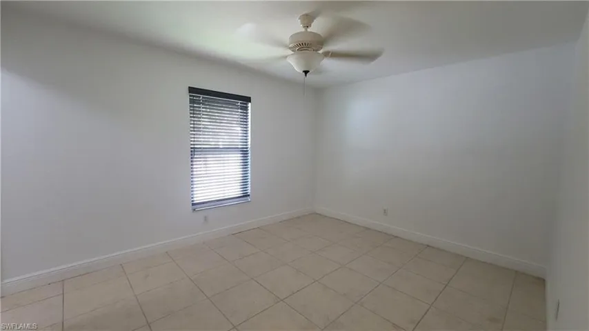 Tiled spare room featuring ceiling fan