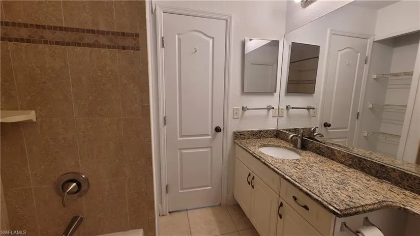 Bathroom featuring tile patterned floors, vanity, and tiled shower / bath combo