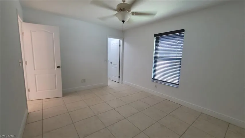 Unfurnished room with ceiling fan and light tile patterned flooring