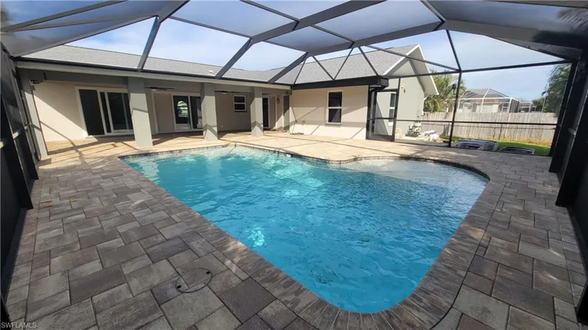 View of swimming pool with glass enclosure, ceiling fan, and a patio area