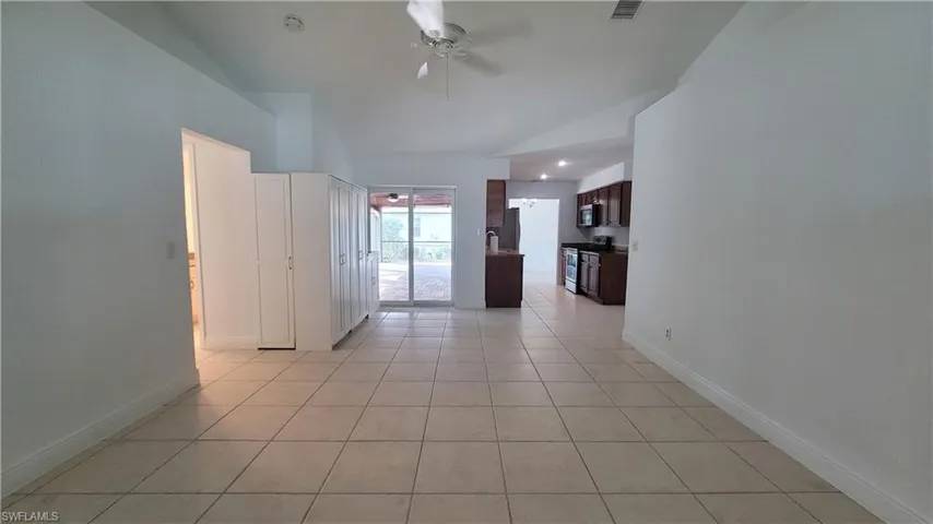 Spare room with ceiling fan, light tile patterned floors, and vaulted ceiling