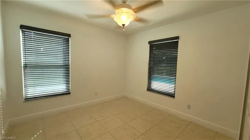 Tiled spare room featuring a wealth of natural light and ceiling fan