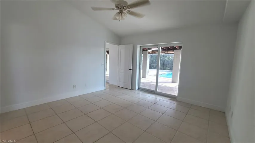 Empty room featuring ceiling fan, lofted ceiling, and light tile patterned floors