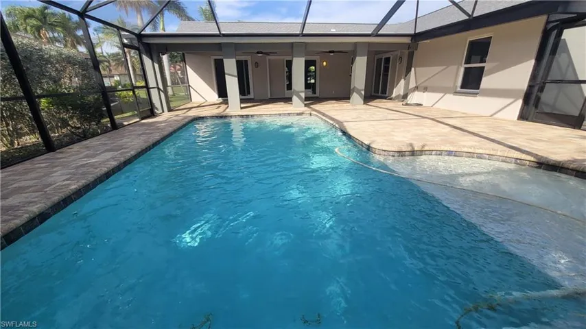 View of pool with ceiling fan, a patio area, and glass enclosure