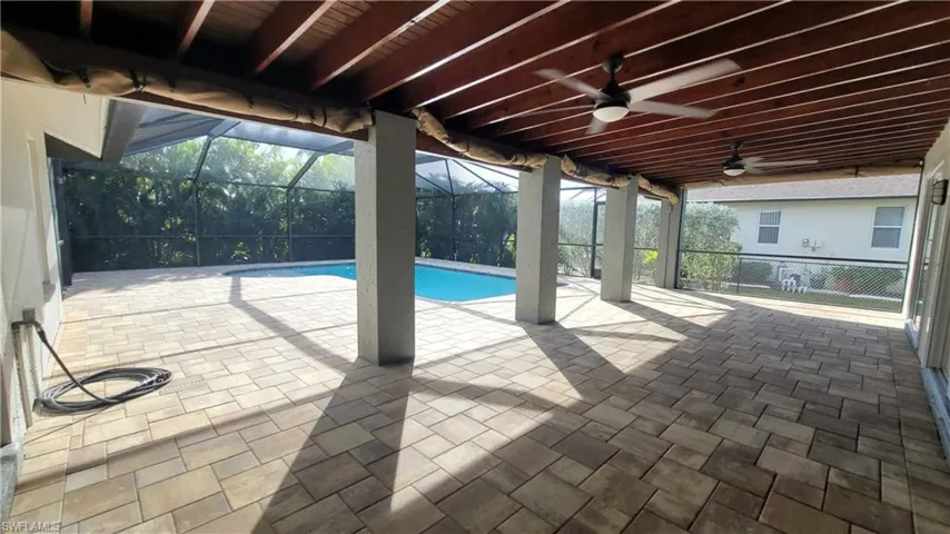 View of swimming pool featuring ceiling fan, a patio, and glass enclosure