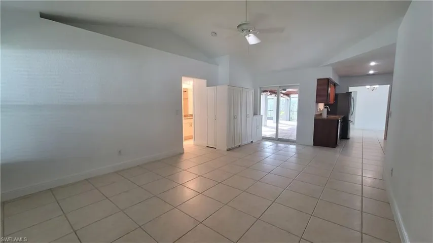 Tiled empty room with ceiling fan and lofted ceiling