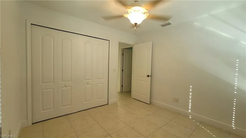 Unfurnished bedroom featuring ceiling fan, light tile patterned flooring, and a closet
