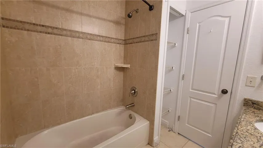 Bathroom with tile patterned flooring, tiled shower / bath combo, and vanity