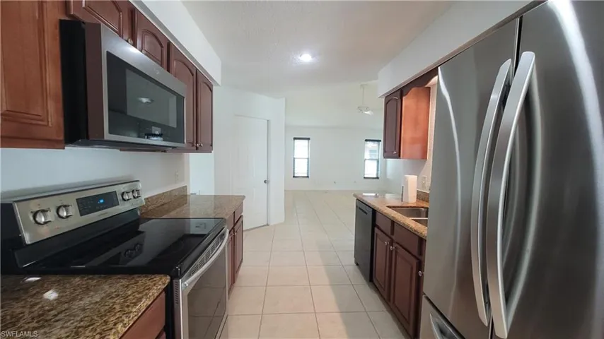 Kitchen featuring dark stone countertops, light tile patterned floors, and appliances with stainless steel finishes