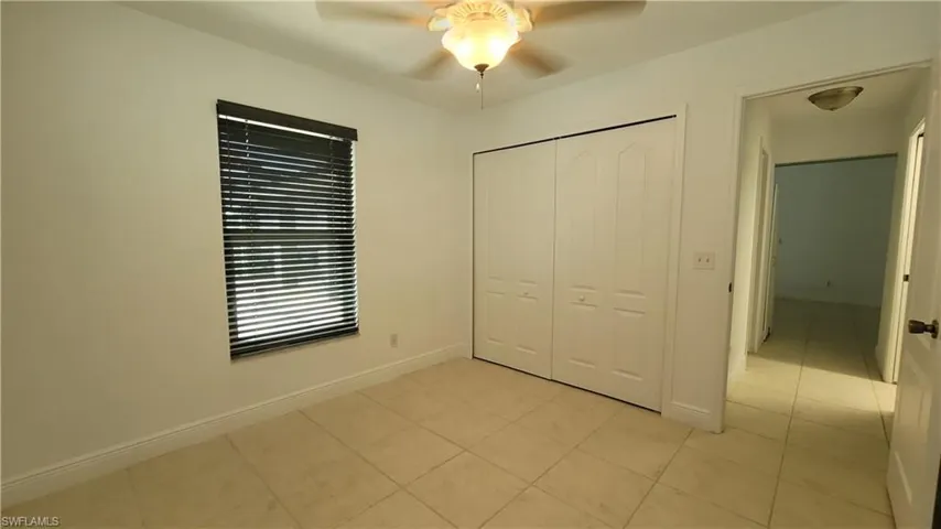 Unfurnished bedroom with ceiling fan, a closet, and light tile patterned floors