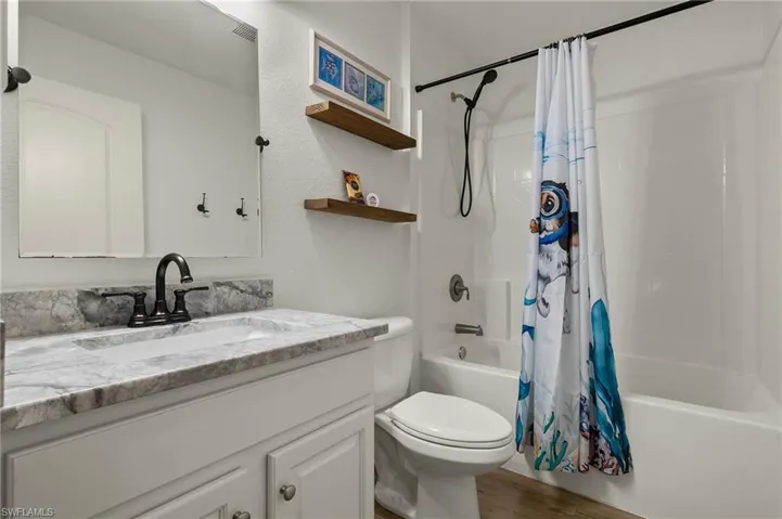Full bathroom with shower / bath combo with shower curtain, wood-type flooring, toilet, and vanity