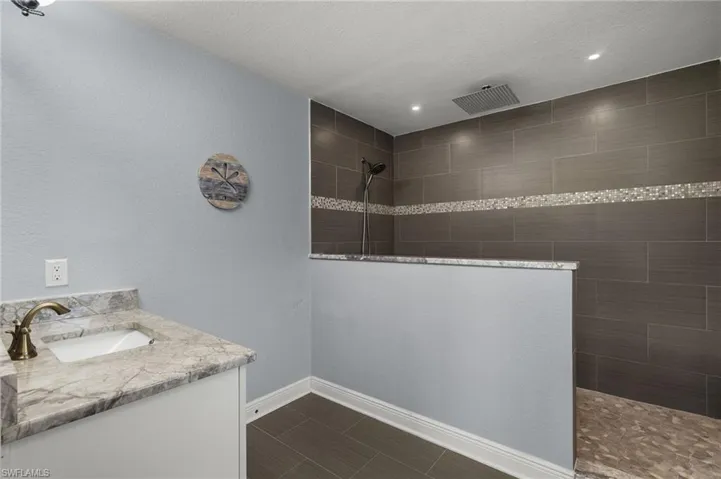 Bathroom with a tile shower, a textured ceiling, and vanity