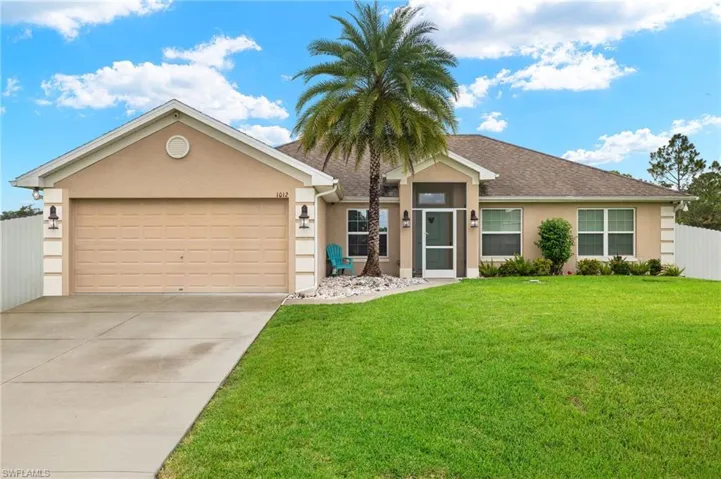 Single story home with a garage and a front lawn