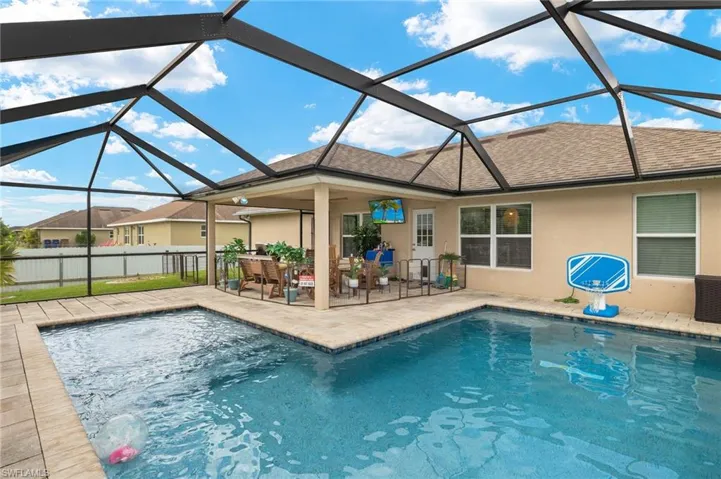View of pool with glass enclosure and a patio