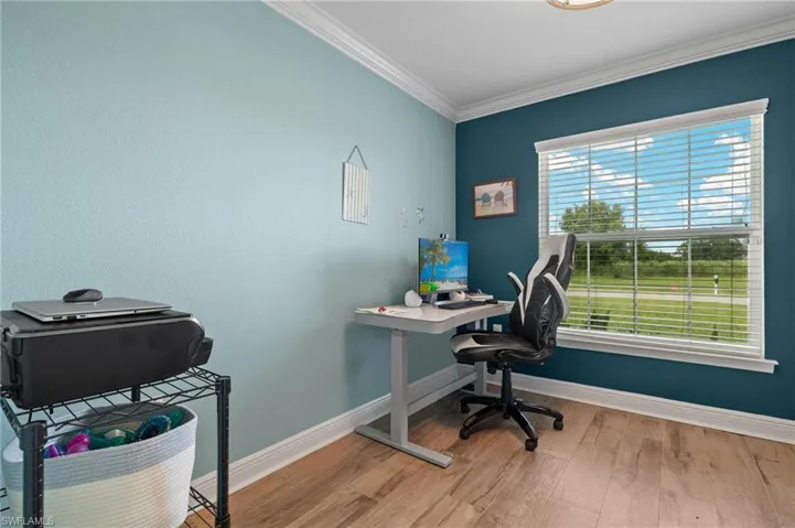 Office area with crown molding and light hardwood / wood-style flooring