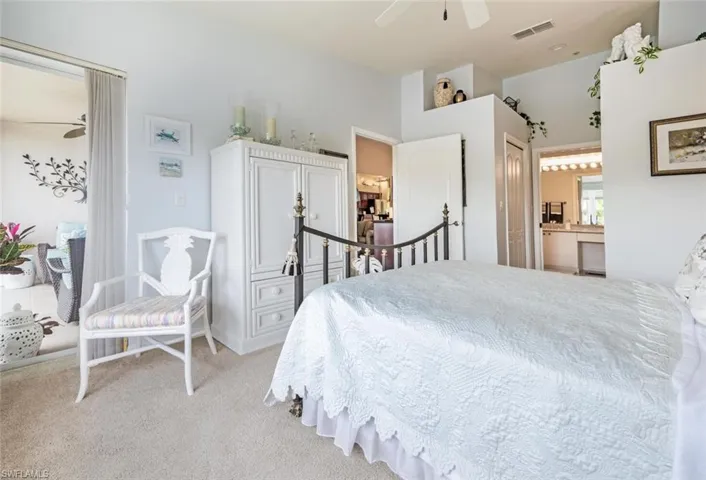 Bedroom with light colored carpet, a ceiling fan, ensuite bathroom, and a closet