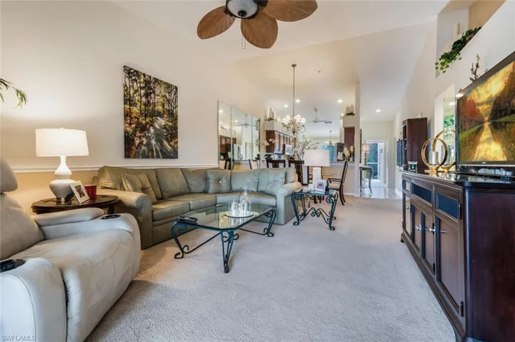 Living area featuring ceiling fan, light carpet, a chandelier, vaulted ceiling, and recessed lighting