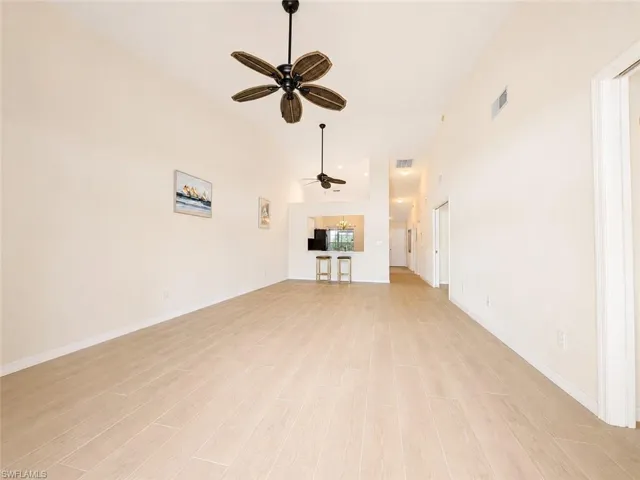 Vaulted ceilings enhance this expansive room featuring light-toned wood-finish flooring