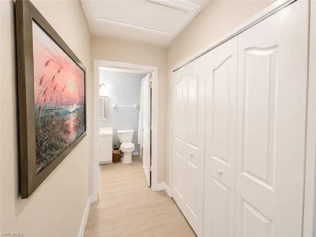 Hallway featuring light wood-finish flooring and a series of white bi-fold doors
