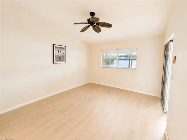 Bright interior space featuring light wood-finish flooring, a ceiling fan, and ample natural light from a window overlooking a body of water