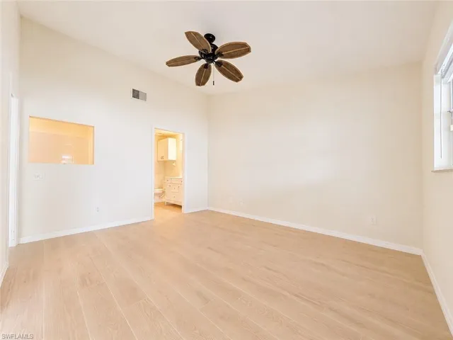 Spacious room featuring wood-finish flooring, a vaulted ceiling, and a ceiling fan with wood-look blades