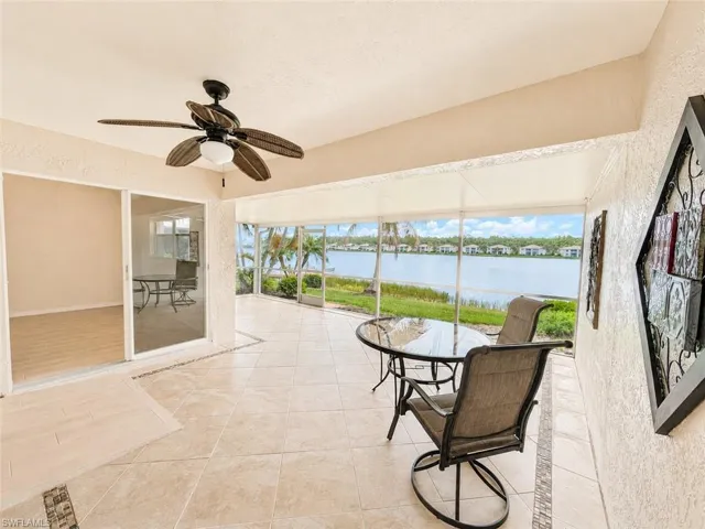 Screened patio featuring ceramic tile flooring with decorative inlay, a ceiling fan with integrated lighting, and expansive water frontage