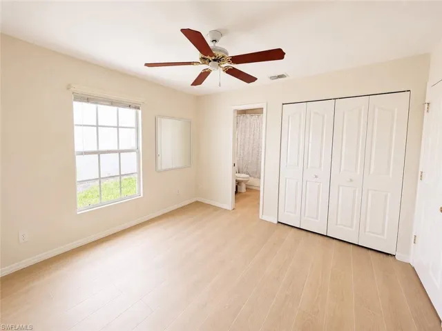 Neutral-toned room featuring light wood-finish flooring and a ceiling fan with dark wood blades