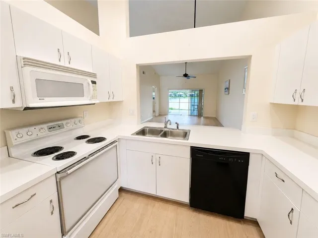 Modern kitchen featuring white cabinetry, light countertops, an electric range, built-in microwave, and a stainless steel double sink