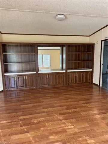Spare room with visible vents, a textured ceiling, wood finished floors, and ornamental molding