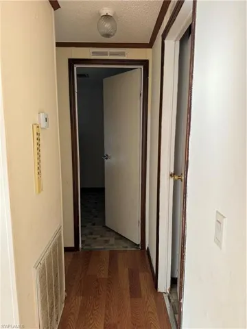 Hallway featuring wood finished floors, visible vents, and a textured ceiling