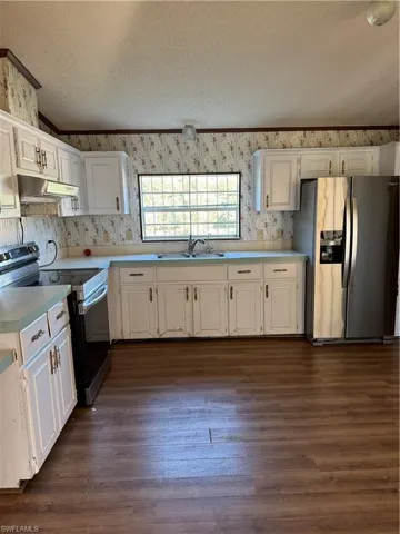 Kitchen featuring fridge, stove, range hood, and wallpapered walls