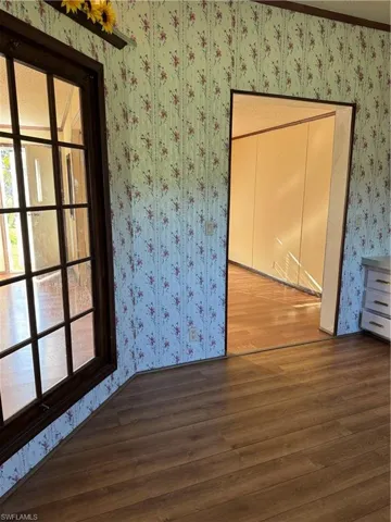 Spare room featuring wallpapered walls and wood finished floors