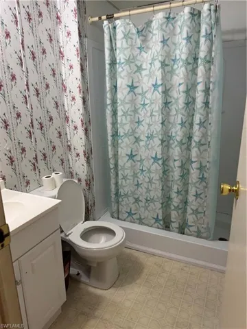 Bathroom with vanity, toilet, and shower / tub combo with curtain