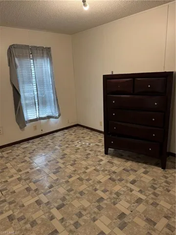 Unfurnished bedroom featuring baseboards and a textured ceiling