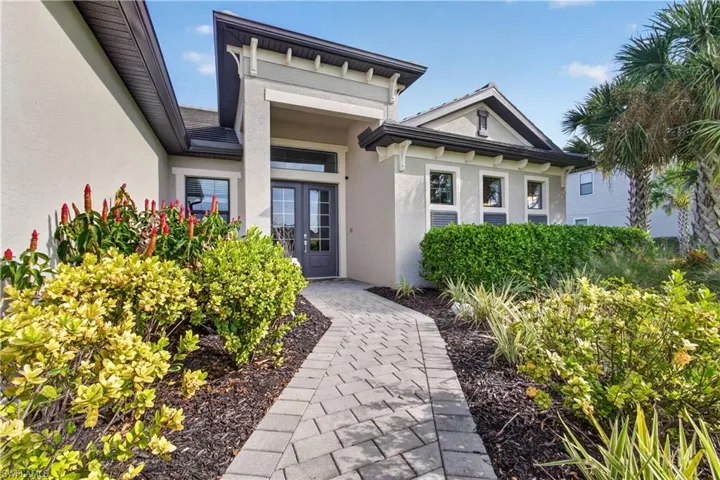 Stucco exterior with a paver walkway, double front entry doors, and established landscaping