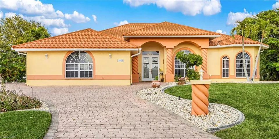 Mediterranean / spanish-style home featuring french doors, a front lawn, stucco siding, and decorative driveway