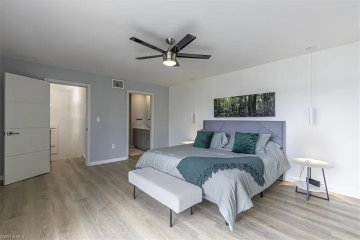Bedroom featuring light wood-style floors, a ceiling fan, and ensuite bath