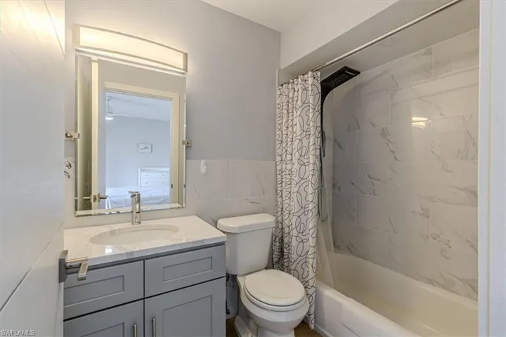 Full bathroom featuring shower / tub combo with curtain, vanity, and tile walls