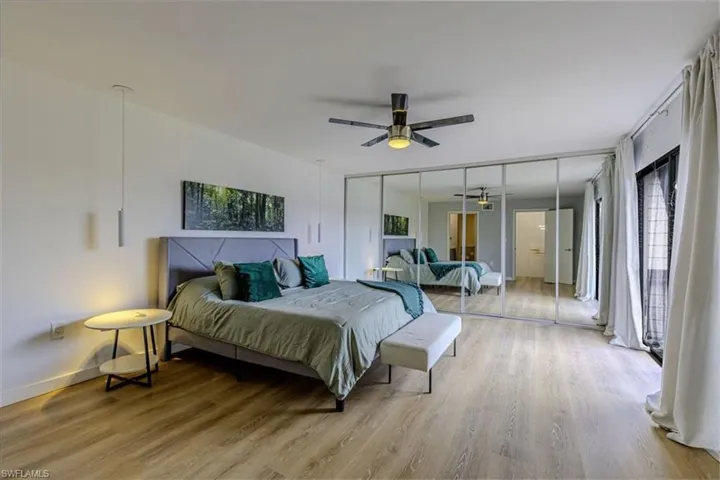 Bedroom with light wood finished floors, multiple windows, and a ceiling fan