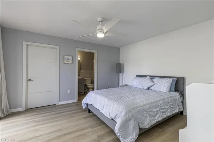 Bedroom with light wood-style floors, a ceiling fan, and ensuite bathroom