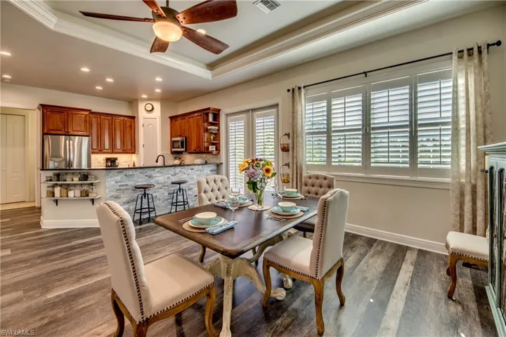 Dining space with ceiling fan, dark wood-type flooring, and a tray ceiling