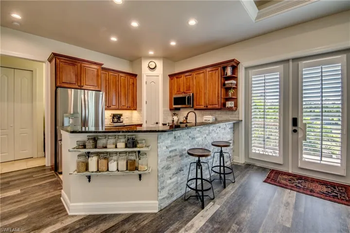Kitchen featuring tasteful backsplash, a kitchen bar, dark hardwood / wood-style floors, appliances with stainless steel finishes, and kitchen peninsula