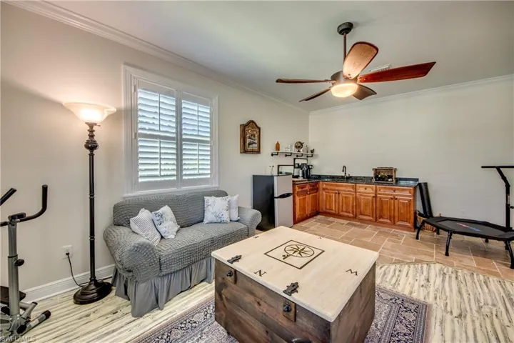 Tiled living room with sink, ceiling fan, and ornamental molding