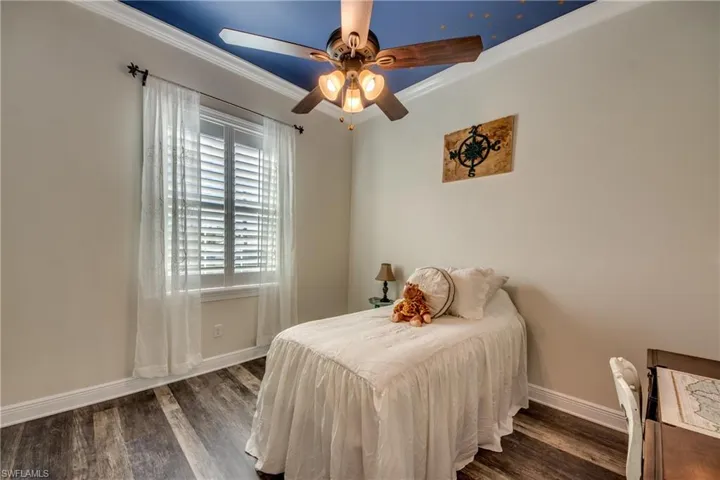 Bedroom featuring ornamental molding, ceiling fan, and dark wood-type flooring