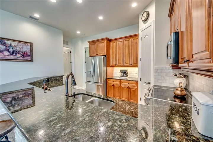 Kitchen featuring sink, decorative backsplash, appliances with stainless steel finishes, and dark stone counters