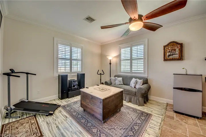 Living room with light tile patterned flooring, ceiling fan, and crown molding